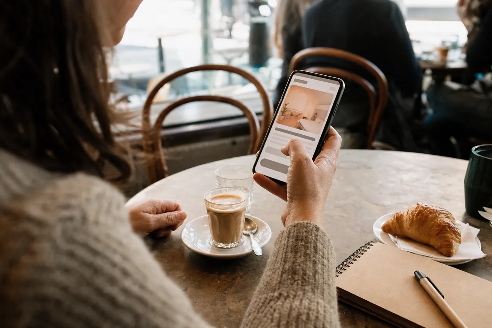 Manos de una mujer revisando un sitio web en el celular en la mesa de un café