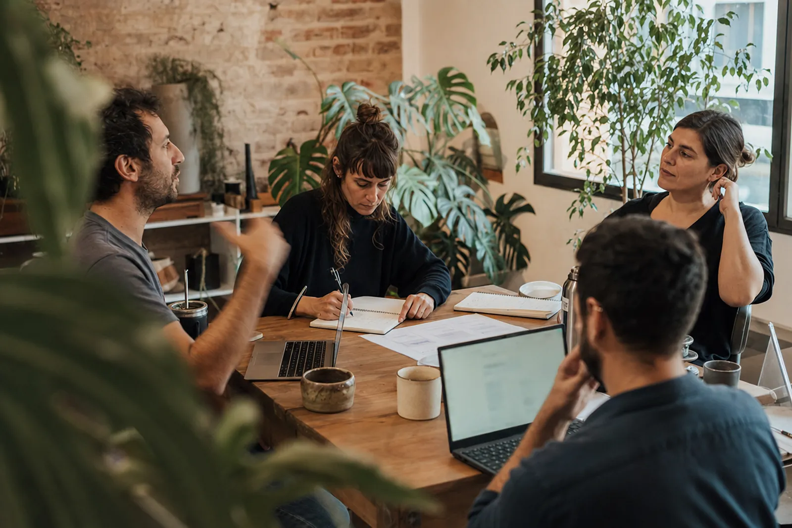 Reunión de trabajo informal alrededor de una mesa con laptops y cuadernos