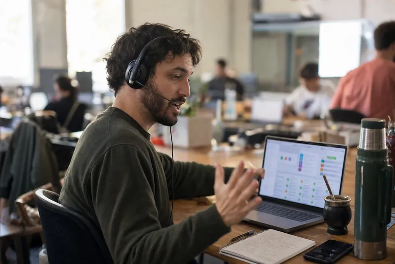 Salesperson on a headset call looking at a dashboard on his laptop